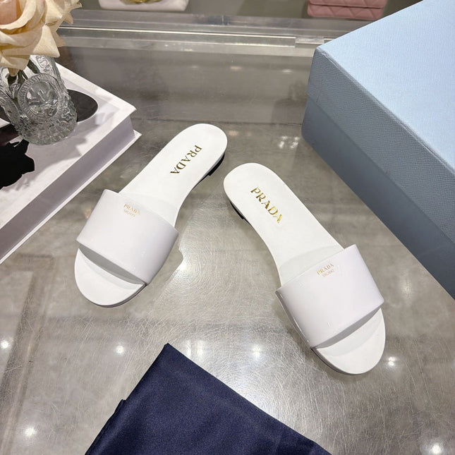 PRADA 26S LOGO EMBOSSED SLIDE SANDALS IN WHITE PATENT CALFSKIN